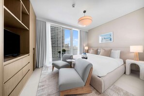 Ein modernes Hotelzimmer mit einem großen Bett, einem Fernseher, einer Sitzecke und einem Balkon mit Blick auf die Stadt.