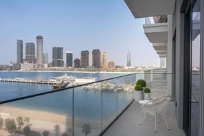 A balcony with a view of a city skyline, a marina, and a beach. - StayShort | Stunning Beachfront 2-Bedroom Apartment Sleeps 6 with Infinity Pool, Skyline Views & Private Beach Access (Dubai)