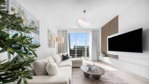 Una sala de estar moderna con un sofá seccional, una mesa de centro y un televisor de pantalla plana montado en la pared.