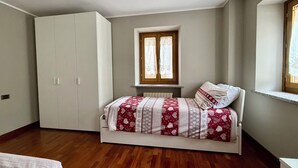 Ein Schlafzimmer mit Bett, Schrank, Fenster und Heizkörper.