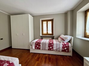 A bedroom with a bed, a wardrobe, a window, and a radiator. - Dolomiti Cadore Home, in the heart of the Cadore Dolomites, 5 minutes from Sappada (san pietro di cadore)