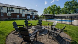 Ein Poolbereich mit Adirondack-Stühlen, einer Feuerstelle und einem Pool.