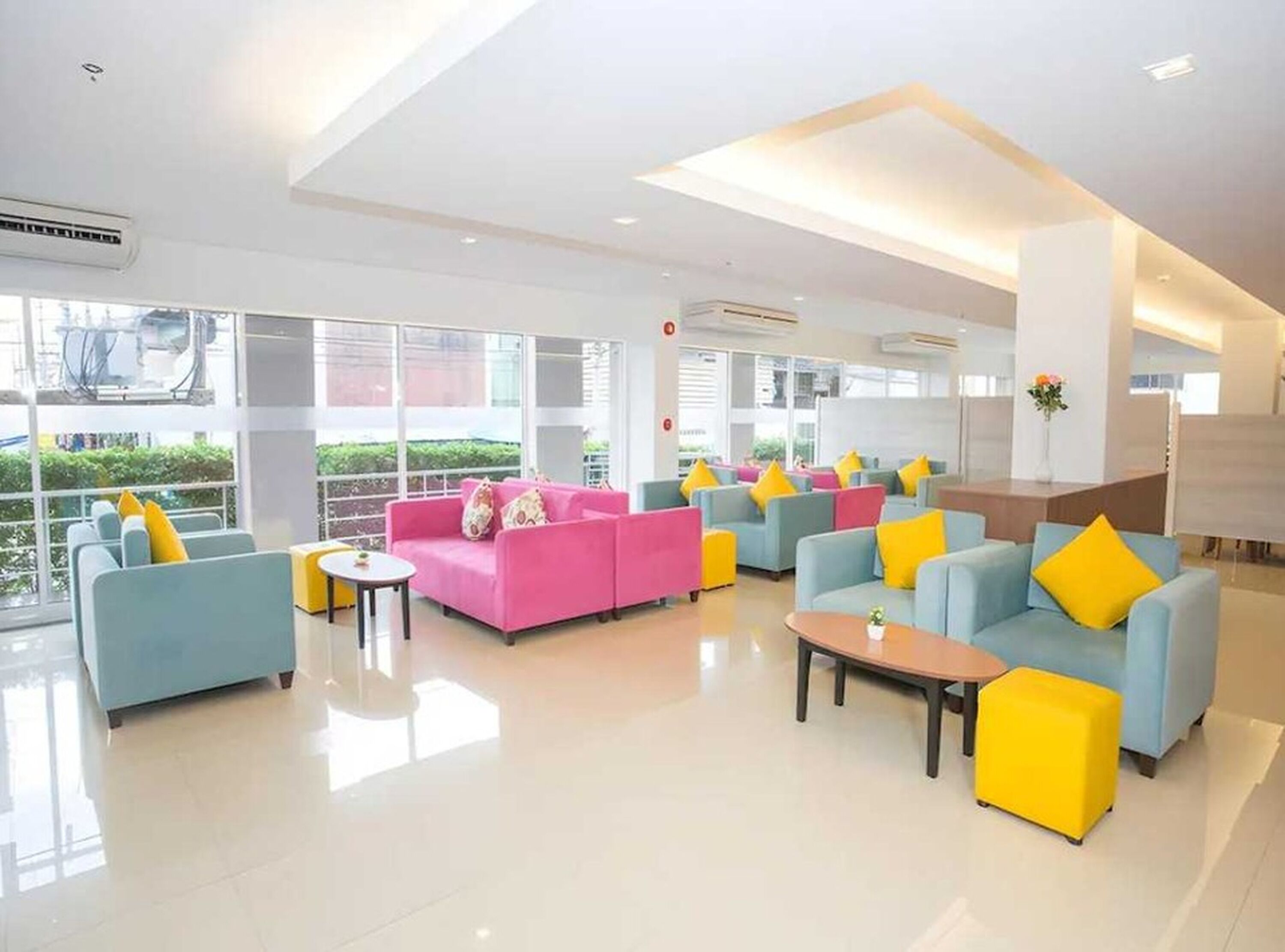 Un moderno vestíbulo de hotel con varias zonas de estar, ventanas amplias y un interior luminoso y limpio.