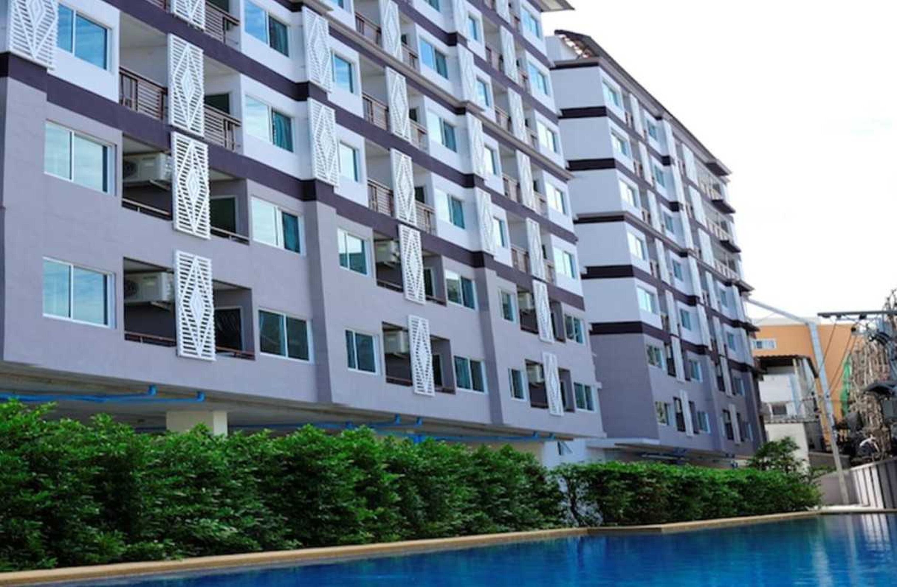 Un hotel de diverses plantes amb balcons, una piscina i un disseny arquitectònic modern.