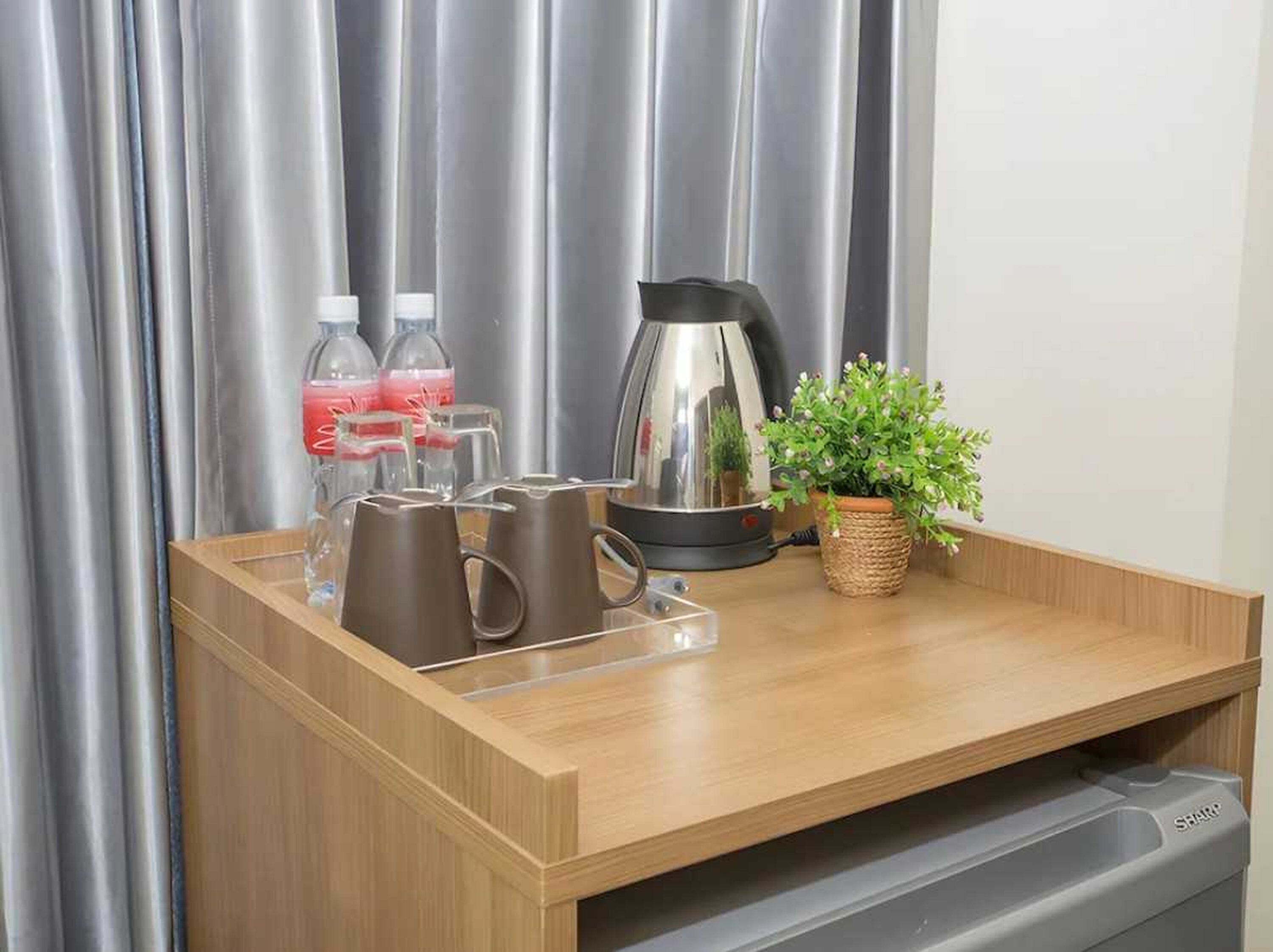 Una encimera de madera con una tetera, dos botellas de agua y una planta en maceta.