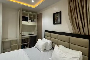 A hotel room with a bed, a wardrobe, a bedside table, and a painting on the wall. - Luxury Apartment, 2 Bedrooms, Kitchenette, Courtyard View (Lagos)