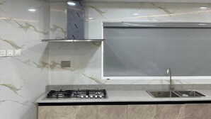 Een keuken met een gasfornuis, een spoelbak en een marmeren achterwand.