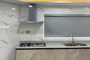 A kitchen with a gas stove, a sink, and a marble backsplash. - Luxury Apartment, 2 Bedrooms, Kitchenette, Courtyard View (Lagos)