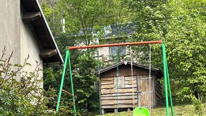 A swing set in a grassy area with a wooden structure in the background. - Oustal Fraïssignol, a comfortable guesthouse (Fraisse-sur-Agout)