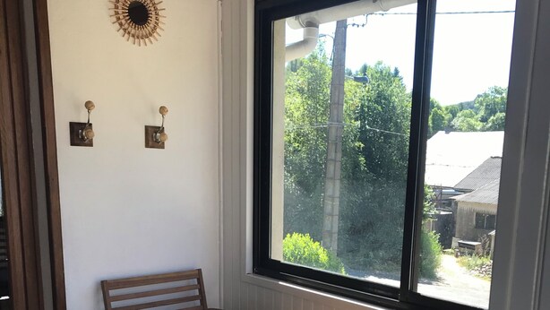 A small room with a window, a wooden chair, a small table, and a decorative wall piece. - Oustal Fraïssignol, a comfortable guesthouse (Fraisse-sur-Agout)