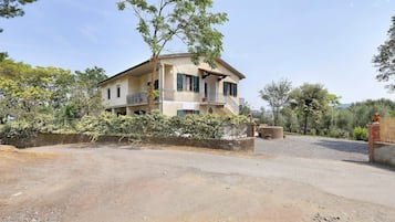 Ein zweistöckiges Haus mit Balkon, umgeben von einem Schotterweg und Grünflächen.
