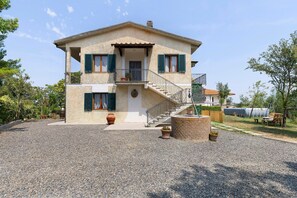 A two-story house with a gravel driveway, a front porch, and a staircase leading to the upper floor. - Apartment 'Terra' with Shared Pool, Garden, and Wi-Fi (Volterra)