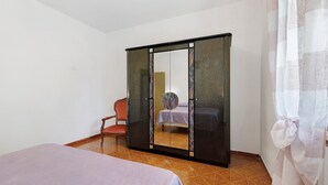 A room with a bed, a chair, and a wardrobe with a mirror. - Apartment 'Terra' with Shared Pool, Garden, and Wi-Fi (Volterra)
