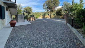 A gravel driveway leading to a building with a balcony, surrounded by trees and a clear sky. - Apartment 'Terra' with Shared Pool, Garden, and Wi-Fi (Volterra)
