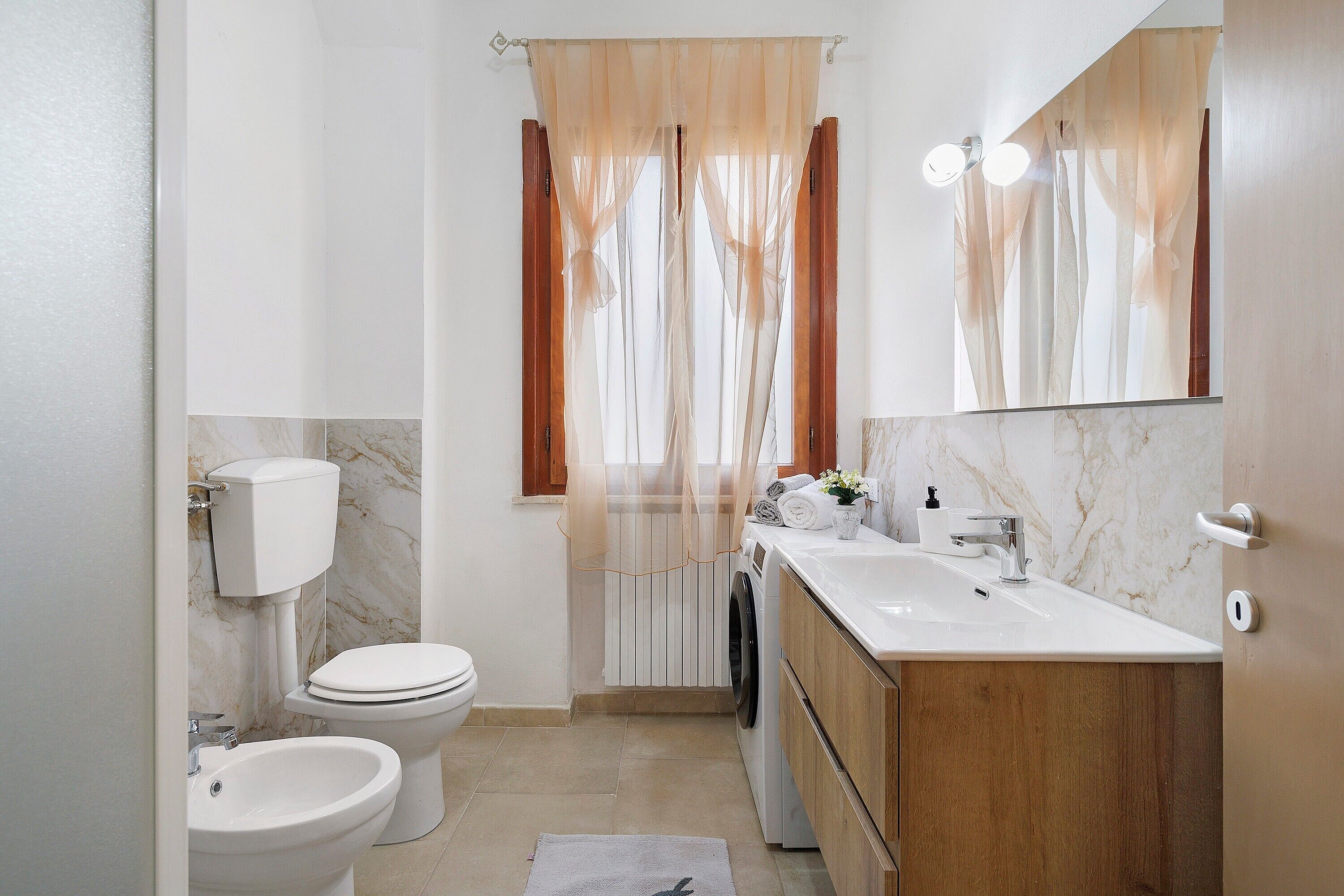 A bathroom with a toilet, bidet, sink, and a mirror.