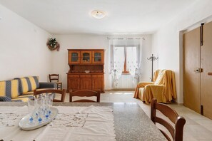A living room with a sofa, chairs, a dining table, and a cabinet. - Apartment 'Terra' with Shared Pool, Garden, and Wi-Fi (Volterra)