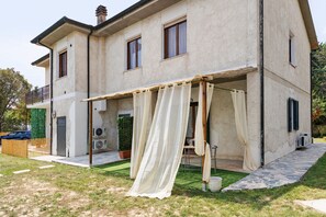 A two-story house with a covered outdoor area, air conditioning units, and a small garden. - Mini appartamento Terra! - Benvenuti a Villamagna di Volterra! (Volterra)