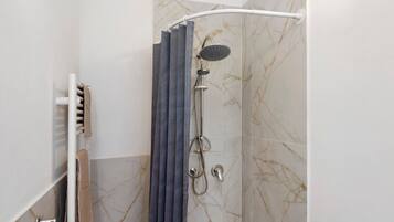 Eine Dusche mit Handbrause und Regendusche, ein Handtuchhalter mit Handtuch sowie eine Wand im Marmor-Design.