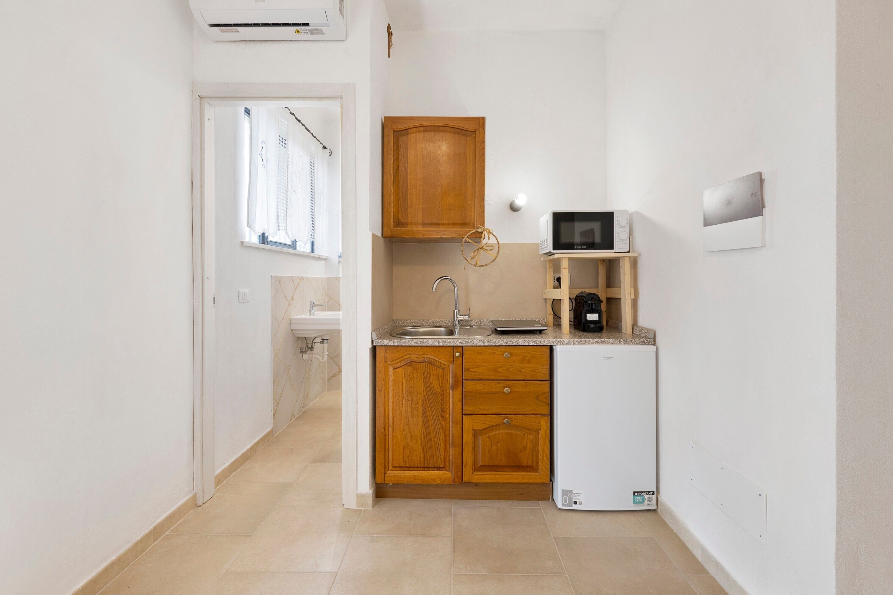 Una cucina compatta con mobili in legno, un frigorifero bianco, un forno a microonde e un lavello.
