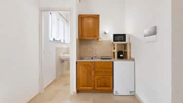 Una cucina compatta con mobili in legno, un frigorifero bianco, un forno a microonde e un lavello.