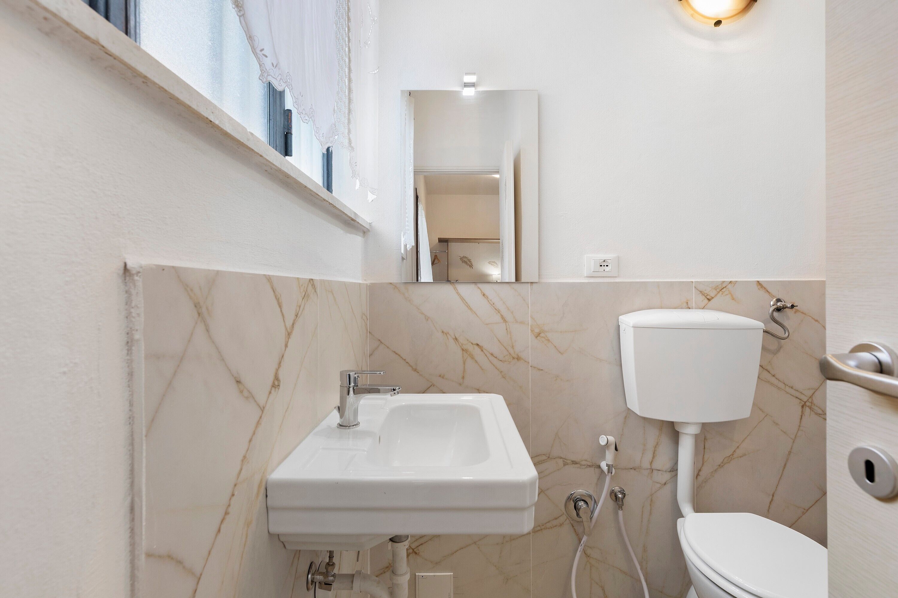 A bathroom with a sink, toilet, and a mirror.
