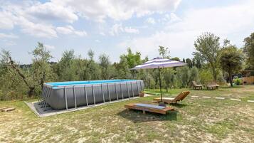Ein Garten mit einem rechteckigen Swimmingpool, Liegestühlen und einem Terrassentisch.
