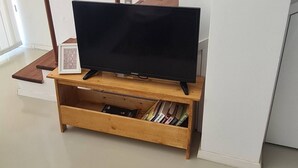 A wooden TV stand with a flat-screen TV, a framed picture on the wall, and a staircase with wooden railings. - Serene 3-bedroom Villa Rental in Köyceğiz, Turkey (Koycegiz)