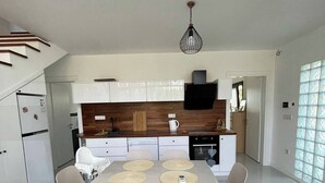 Una cocina moderna con armarios blancos, una mesa de comedor con cuatro sillas y una lámpara colgante.