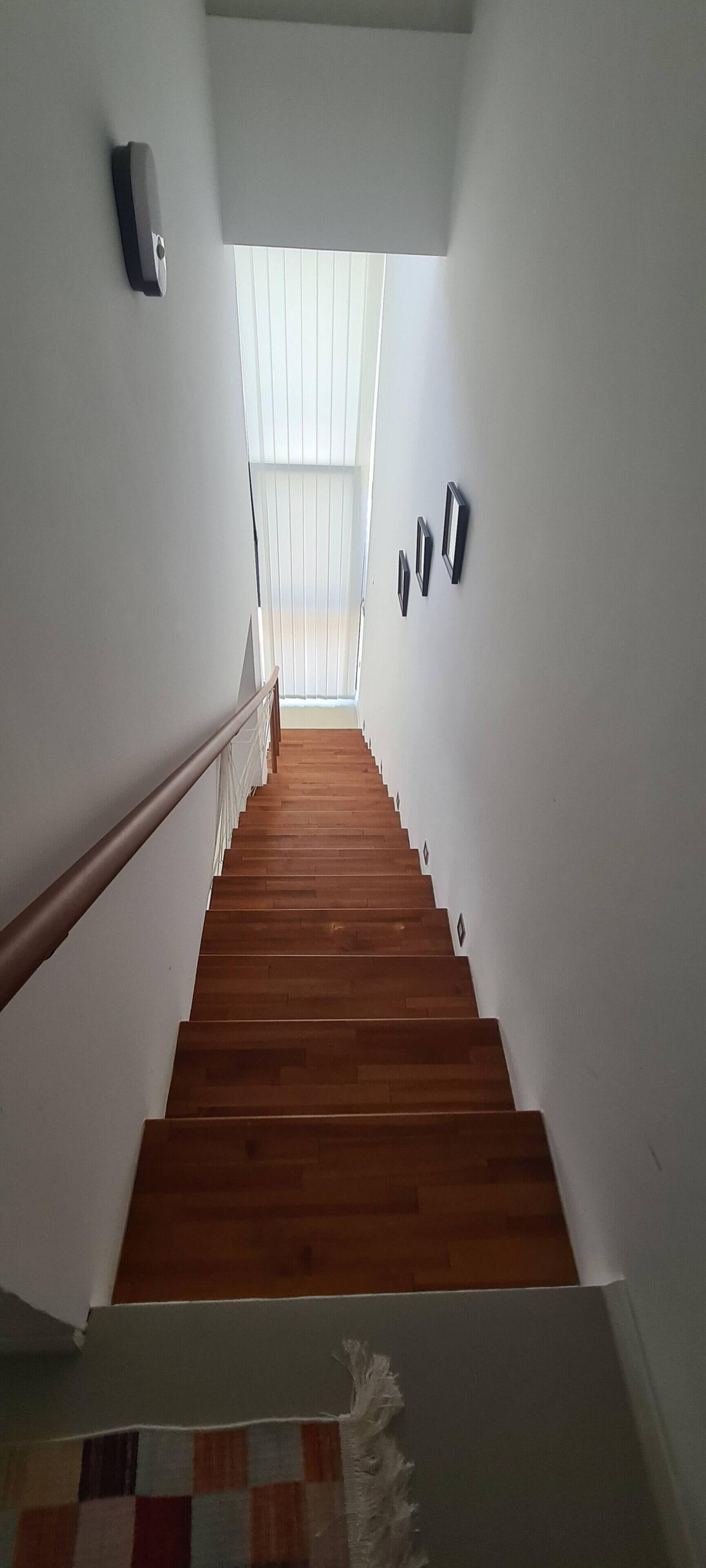 Una escalera de madera que conduce a una habitación con tragaluces.
