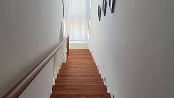 Una escalera de madera que conduce a una habitación con tragaluces.