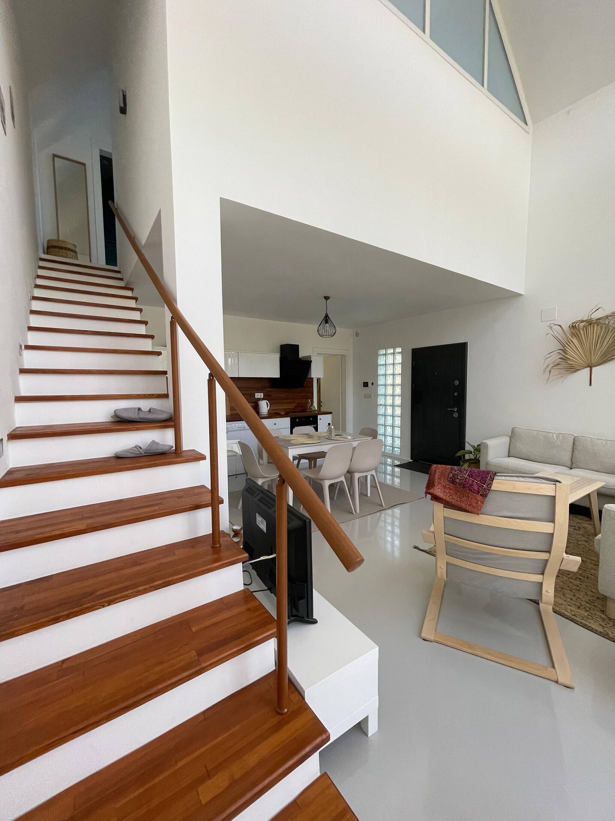 A modern interior with a wooden staircase, a dining area, and a living space.