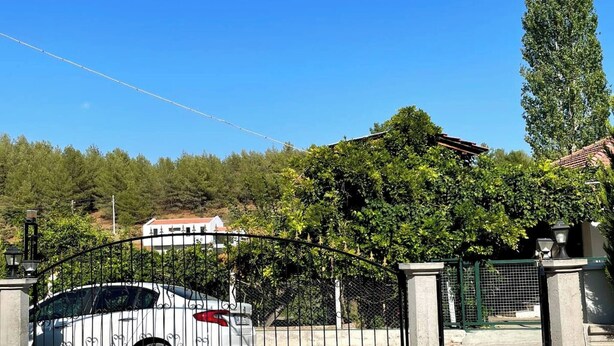 A gated entrance with a stone-paved driveway leading to a building, surrounded by trees and a clear blue sky. - Serene 3-bedroom Villa Rental in Köyceğiz, Turkey (Koycegiz)