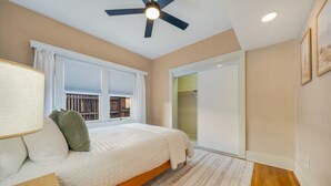 A bedroom with a bed, a ceiling fan, a window with blinds, and a sliding door leading to a bathroom. - Sam Hughes / Carport / Updated / 3BR 3BA / Fenced (Tucson)