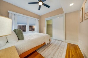 A bedroom with a bed, a ceiling fan, a window with blinds, and a sliding door leading to a bathroom. - Sam Hughes / Carport / Updated / 3BR 3BA / Fenced (Tucson)