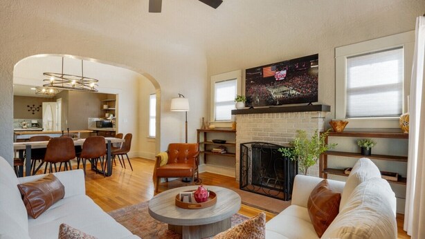 A spacious living room with a fireplace, a dining area, and a kitchen visible through an archway. - Sam Hughes / Carport / Updated / 3BR 3BA / Fenced (Tucson)