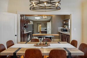 A modern kitchen with dark wood cabinets, a central island, and a pendant light fixture. - Sam Hughes / Carport / Updated / 4BR 3BA / Fenced (Tucson)