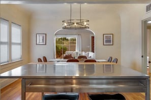 A dining area with a large table, chairs, a modern chandelier, and framed pictures on the walls. - Sam Hughes / Carport / Updated / 3BR 3BA / Fenced (Tucson)