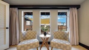 A room with two wicker chairs facing a small round table with a vase, large windows with curtains, and a view of the outside. - Sam Hughes / Carport / Updated / 3BR 3BA / Fenced (Tucson)