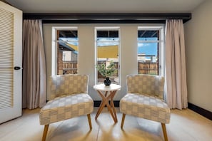 A room with two wicker chairs facing a small round table with a vase, large windows with curtains, and a view of the outside. - Sam Hughes / Carport / Updated / 3BR 3BA / Fenced (Tucson)