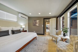 A bedroom with a large bed, bedside table, lamp, and a view of the dining area. - Sam Hughes / Carport / Updated / 4BR 3BA / Fenced (Tucson)