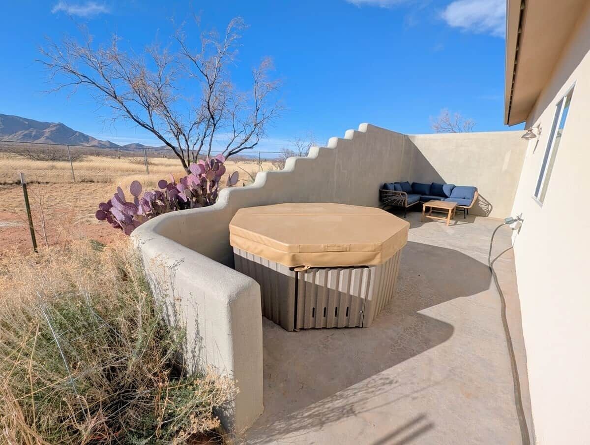 A patio with a hot tub, outdoor seating, and a cactus plant.
