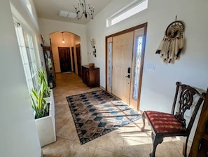 A hallway with a patterned rug, a wooden bench, a dreamcatcher, and a door with a window. - Expansive ranch house w/ guest suite for groups (Cochise County)