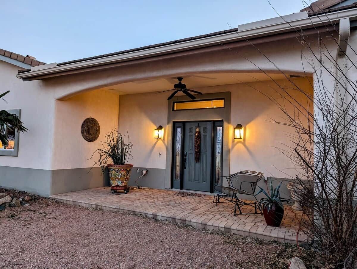 Una casa con porche delantero, ventilador de techo, puerta doble y dos luces fijadas en la pared.