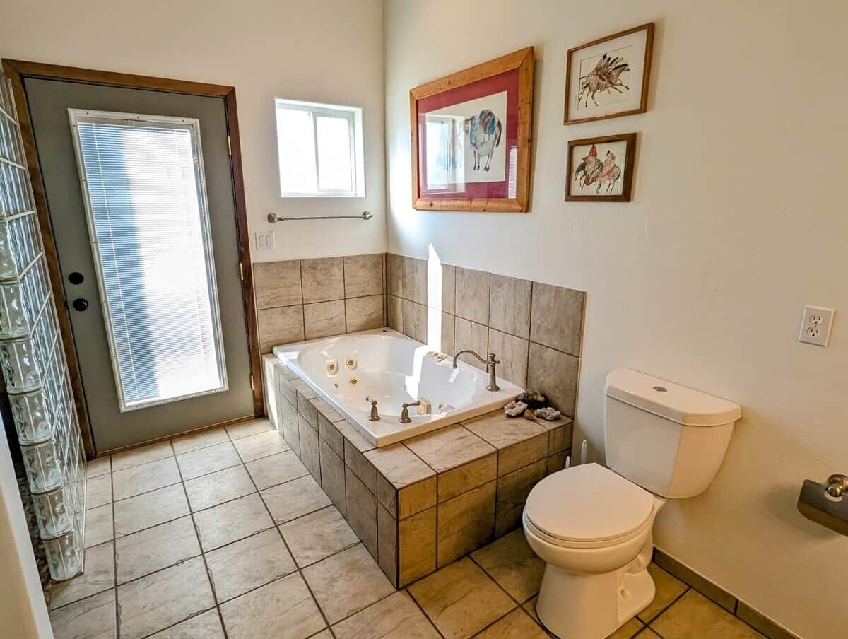 A bathroom with a bathtub, toilet, and a window.