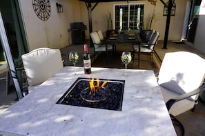 An outdoor patio with a table, chairs, a fire pit, and a bottle of wine. - Spacious 2BR Getaway w/Hot Tub (Cochise County)
