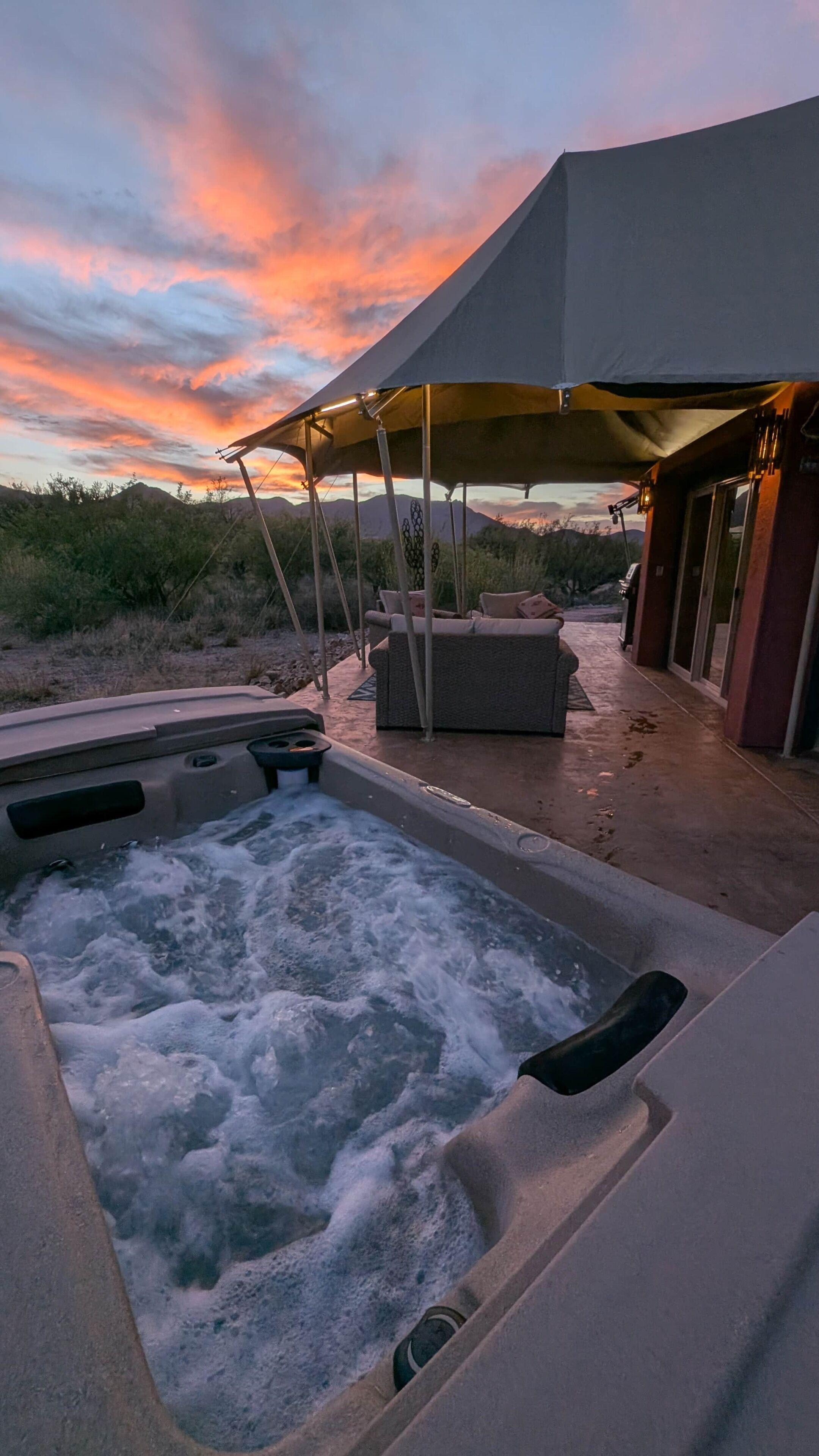 Un jacuzzi con zona de patio, un espacio de estar techado y vistas al paisaje circundante.