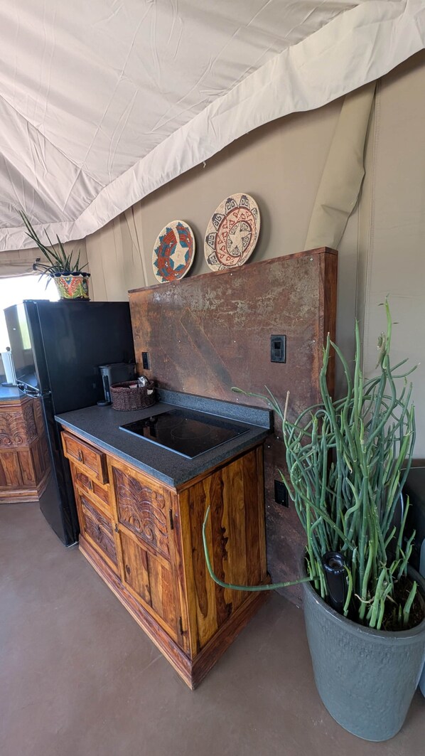 Una cocina con un armario de madera, una encimera negra y una planta en maceta.