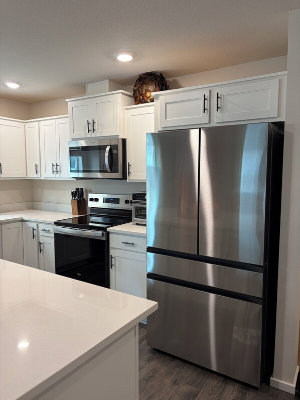 A modern kitchen with white cabinetry, stainless steel appliances, and a central island. - Welcome to Your Pacific Northwest Retreat (Vancouver)