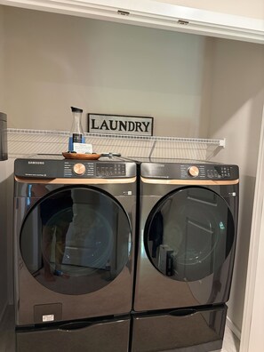A laundry area with two Samsung front-loading washers and a drying rack.