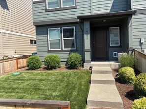 A two-story residential building with a front door, windows, and a well-maintained lawn.